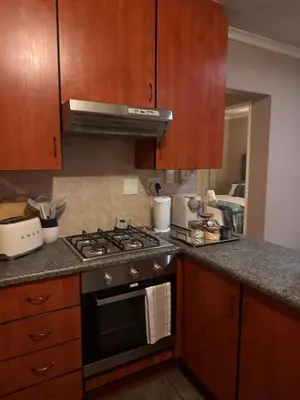 a kitchen with wooden cabinets and a stove top oven at Haven on Glen in Johannesburg