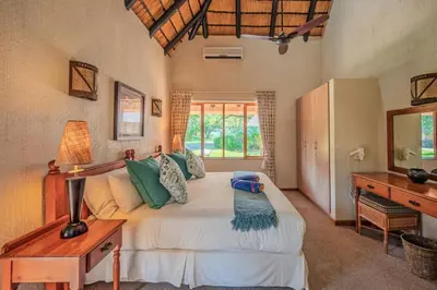 a bedroom with a bed and a desk and a window at Kruger Park Lodge Unit No 303 in Hazyview