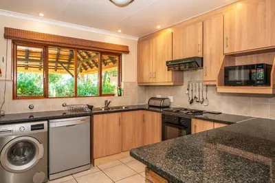 a kitchen with wooden cabinets and a dishwasher at Kruger Park Lodge Unit No 303 in Hazyview
