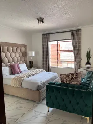 a bedroom with a bed and a couch and a window at 3 bedroom holiday apartment in Pretoria East in Pretoria