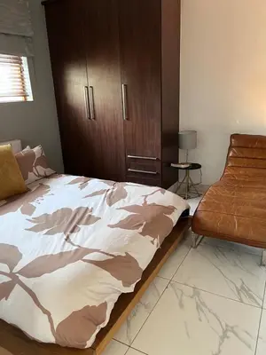 a bedroom with a bed and a chair at 3 bedroom holiday apartment in Pretoria East in Pretoria