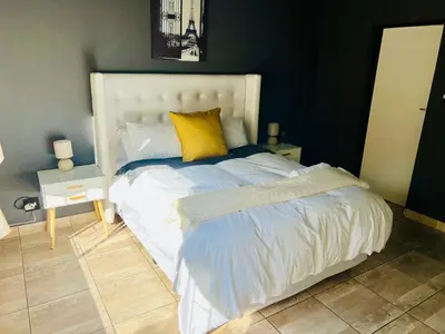 a bedroom with a white bed with a yellow pillow at 13 Orion Aparment in Polokwane