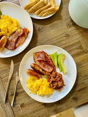 three plates of breakfast food on a wooden table at 13 Orion Aparment in Polokwane