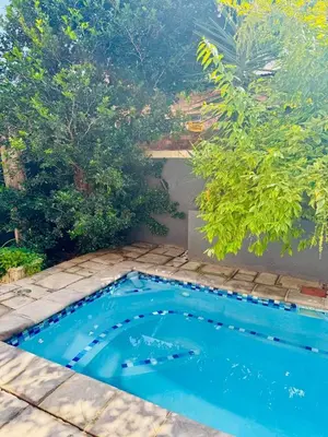a small blue swimming pool in a yard with trees at 13 Orion Aparment in Polokwane