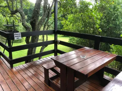 a wooden table on a wooden deck with a tree at Zur Alten Mine in Graskop