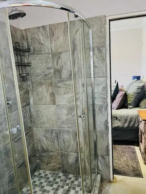 a shower with a glass door in a bedroom at Clarkys Bucketlist Dullstroom in Dullstroom