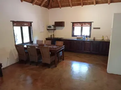 a living room with a table and a kitchen at Iphupho Bush Lodge, Ba-Phalaborwa Golf Estate in Phalaborwa