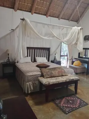 a bedroom with a bed and a couch in it at Iphupho Bush Lodge, Ba-Phalaborwa Golf Estate in Phalaborwa