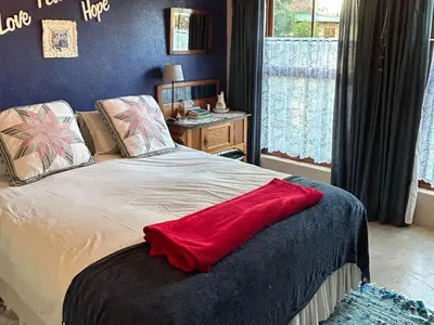 a bedroom with a bed with a red blanket on it at Legodimo Cottage in Dullstroom
