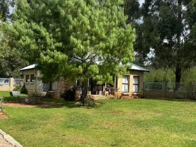 a small house with a tree in a yard at Legodimo Cottage in Dullstroom