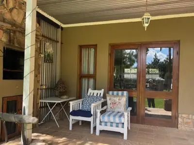a porch with two chairs and a table and a window at Legodimo Cottage in Dullstroom