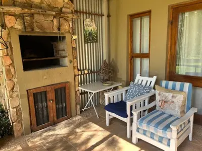 a porch with two chairs and a table and a television at Legodimo Cottage in Dullstroom