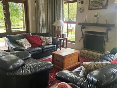 a living room with leather furniture and a fireplace at Legodimo Cottage in Dullstroom