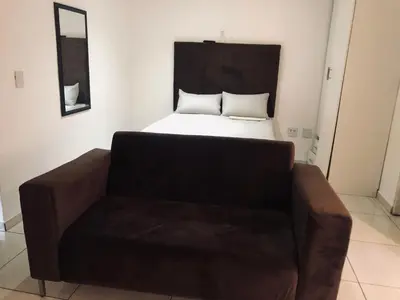 a bed and a couch in a small room at Uncle Charles Guesthouse in Pretoria