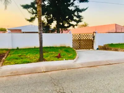 a house with a white fence and a driveway at Uncle Charles Guesthouse in Pretoria