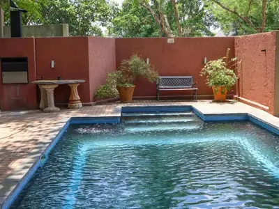 a swimming pool with a bench next to a red wall at Willow Inn in Nelspruit