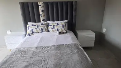 a bedroom with a large bed with a black headboard at Backyard Stay in Pretoria