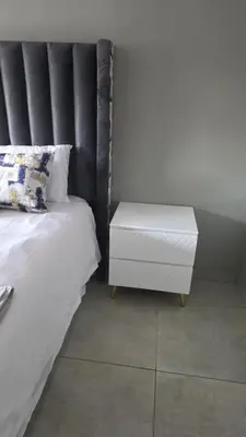 a bed with a black headboard and a white night stand at Backyard Stay in Pretoria