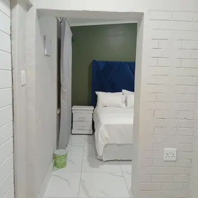 a bedroom with a bed with a blue head board at Backyard Stay in Pretoria