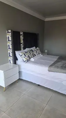 a bedroom with a large white bed and a nightstand at Backyard Stay in Pretoria
