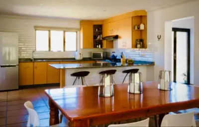 a kitchen with a wooden table and some chairs at Riverbend on Komati in Machadodorp