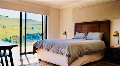 a bedroom with a large bed and a large window at Riverbend on Komati in Machadodorp