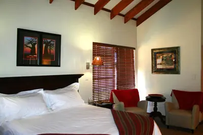 a bedroom with a bed and two chairs and a window at Africa House Guesthouse in Centurion