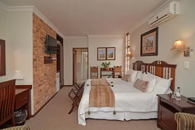 a bedroom with a large bed and a brick wall at Africa House Guesthouse in Centurion
