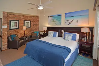 a bedroom with a bed and a chair and a ceiling fan at Africa House Guesthouse in Centurion