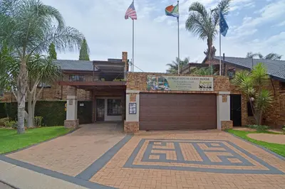 a brick house with a garage and two flags at Africa House Guesthouse in Centurion