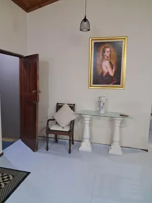 a room with a table and a painting and a chair at Serene Exclusive Country Retreat in White River