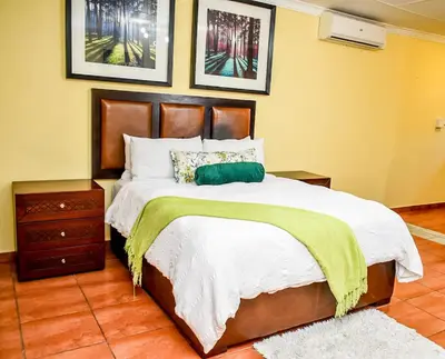 a bedroom with a bed with a green blanket on it at Phabema Guest House in Steelpoort
