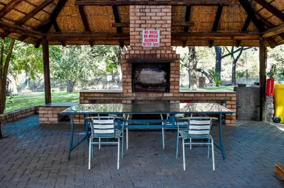 a patio with a table and chairs and a fireplace at Phabema Guest House in Steelpoort