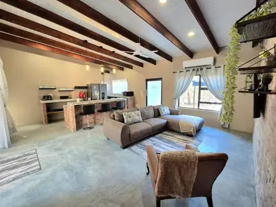 a large living room with a couch and a kitchen at Warthog's Retreat in Marloth Park