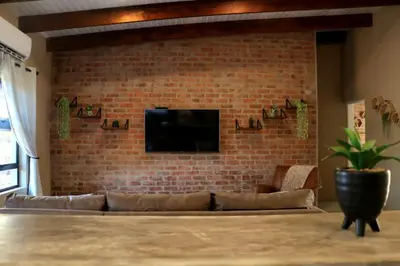 a living room with a couch and a brick wall at Warthog's Retreat in Marloth Park