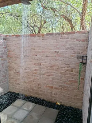 a shower in a brick wall with a waterfall at Warthog's Retreat in Marloth Park