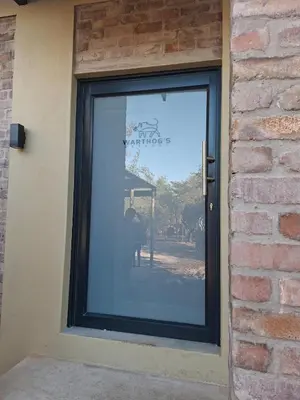 a window with a reflection of a person in it at Warthog's Retreat in Marloth Park