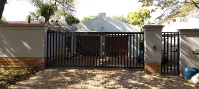 a black metal gate with a white fence at Faerie Glen B&B in Pretoria