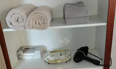 a bathroom shelf with towels and a lamp on it at Faerie Glen B&B in Pretoria