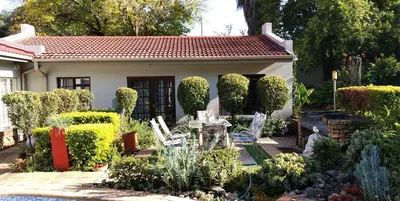 a garden with a table and chairs in front of a house at Faerie Glen B&B in Pretoria