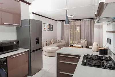 a kitchen and living room with a stove top oven at Closer to Home Luxury Apartments in Midrand
