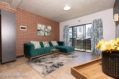 a living room with a green couch and a brick wall at Smart Apartment Luxury in Midrand