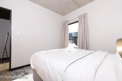 a white bedroom with a bed and a window at Smart Apartment Luxury in Midrand