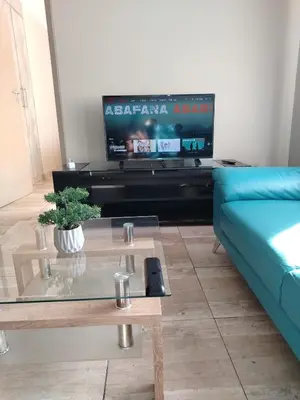 a living room with a blue couch and a tv at Capital Heights in Pretoria