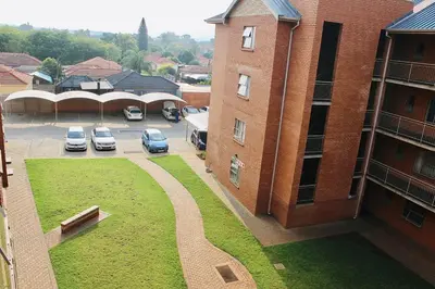 a building with cars parked in a parking lot at Capital Heights in Pretoria