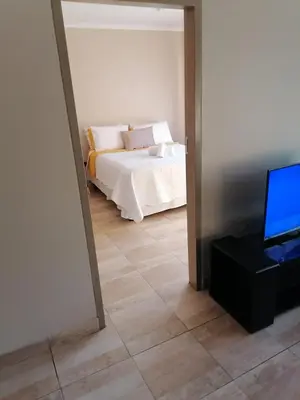 a bedroom with a bed and a flat screen tv at Capital Heights in Pretoria