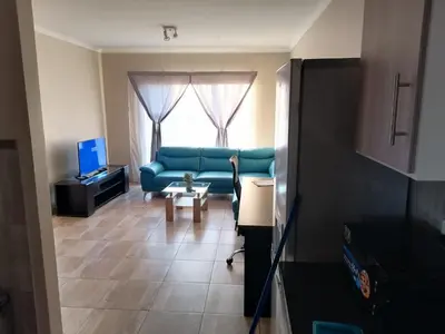 a living room with a blue couch and a window at Capital Heights in Pretoria