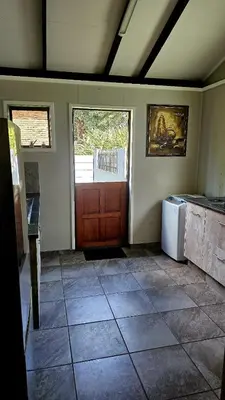a room with a kitchen with a refrigerator and a door at CasaMari guesthouse in Pretoria