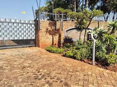 a brick driveway with a fence and trees and plants at CasaMari guesthouse in Pretoria