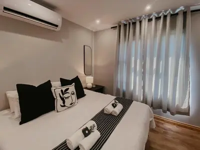 a bedroom with a bed with black and white pillows at Sable Block Self-Catering in Musina